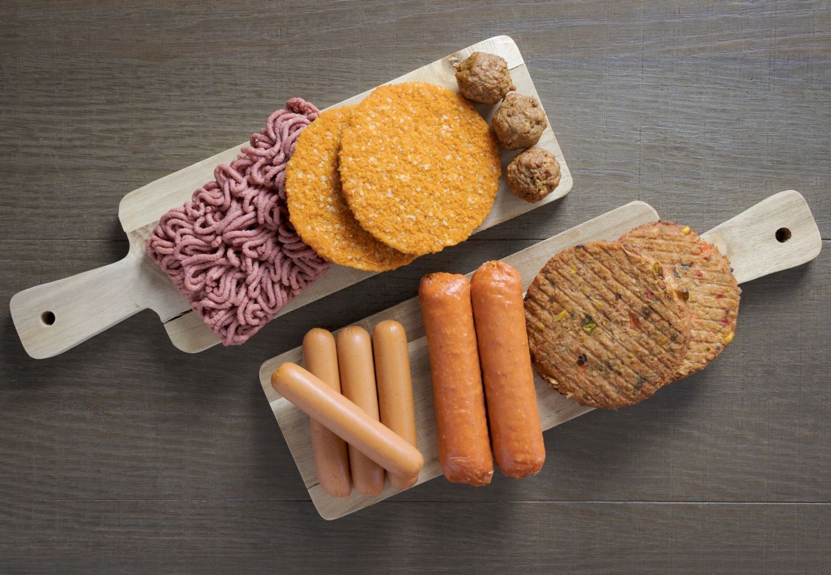 Vegane Fleischersatzprodukte werden präsentiert auf zwei Schneidebrettern aus Holz. 