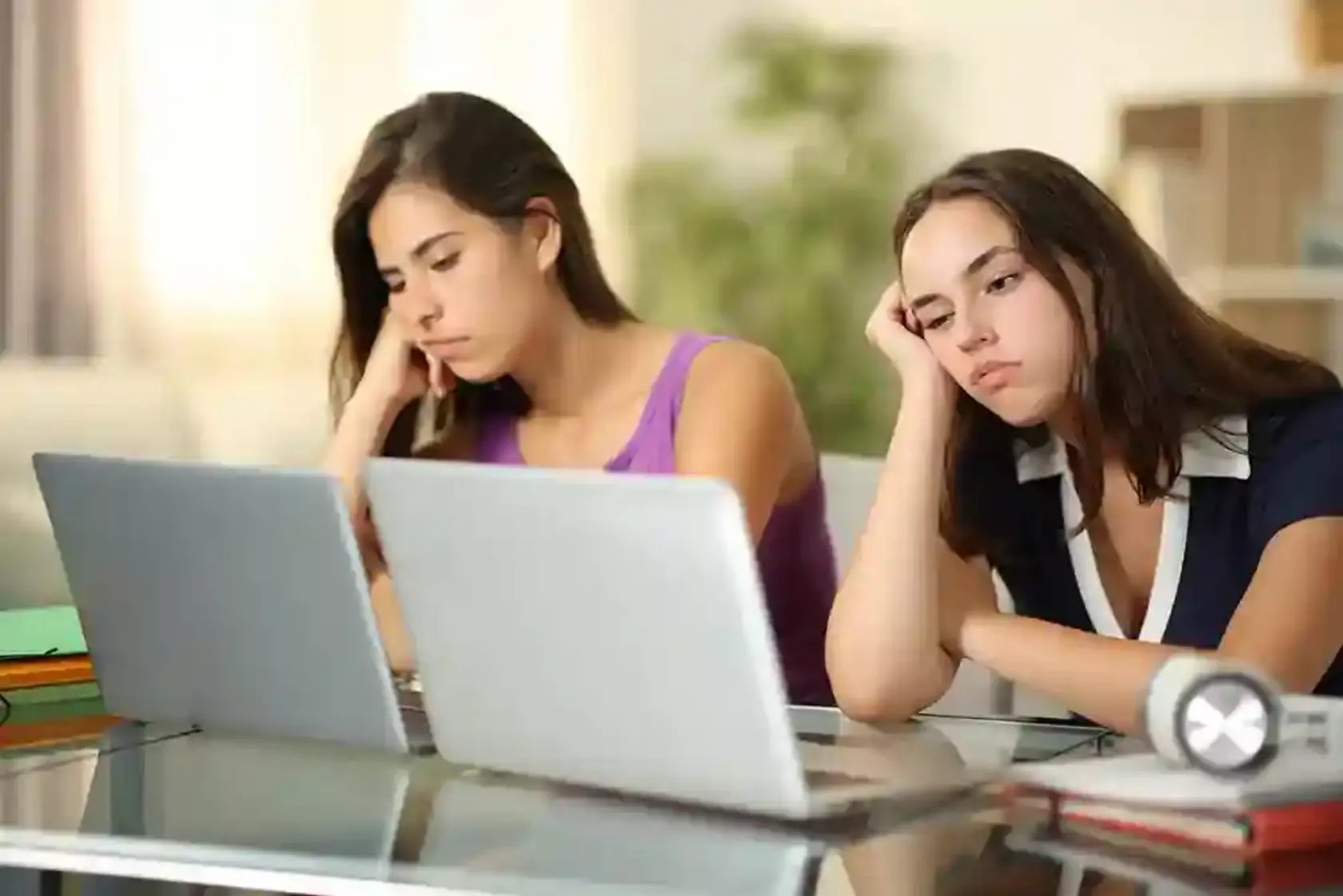 Zwei junge Frauen sitzen vor ihren Laptops, die eine extrem unkonzentriert.