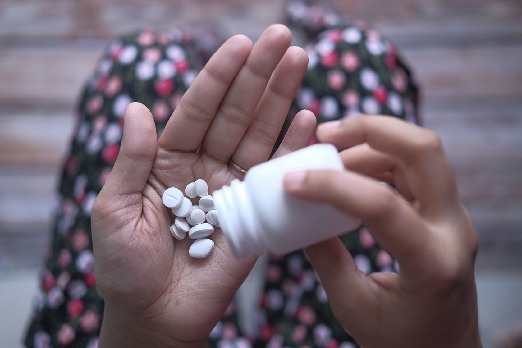 Mensch schüttet sich Tabletten aus einer Packung auf die Hand