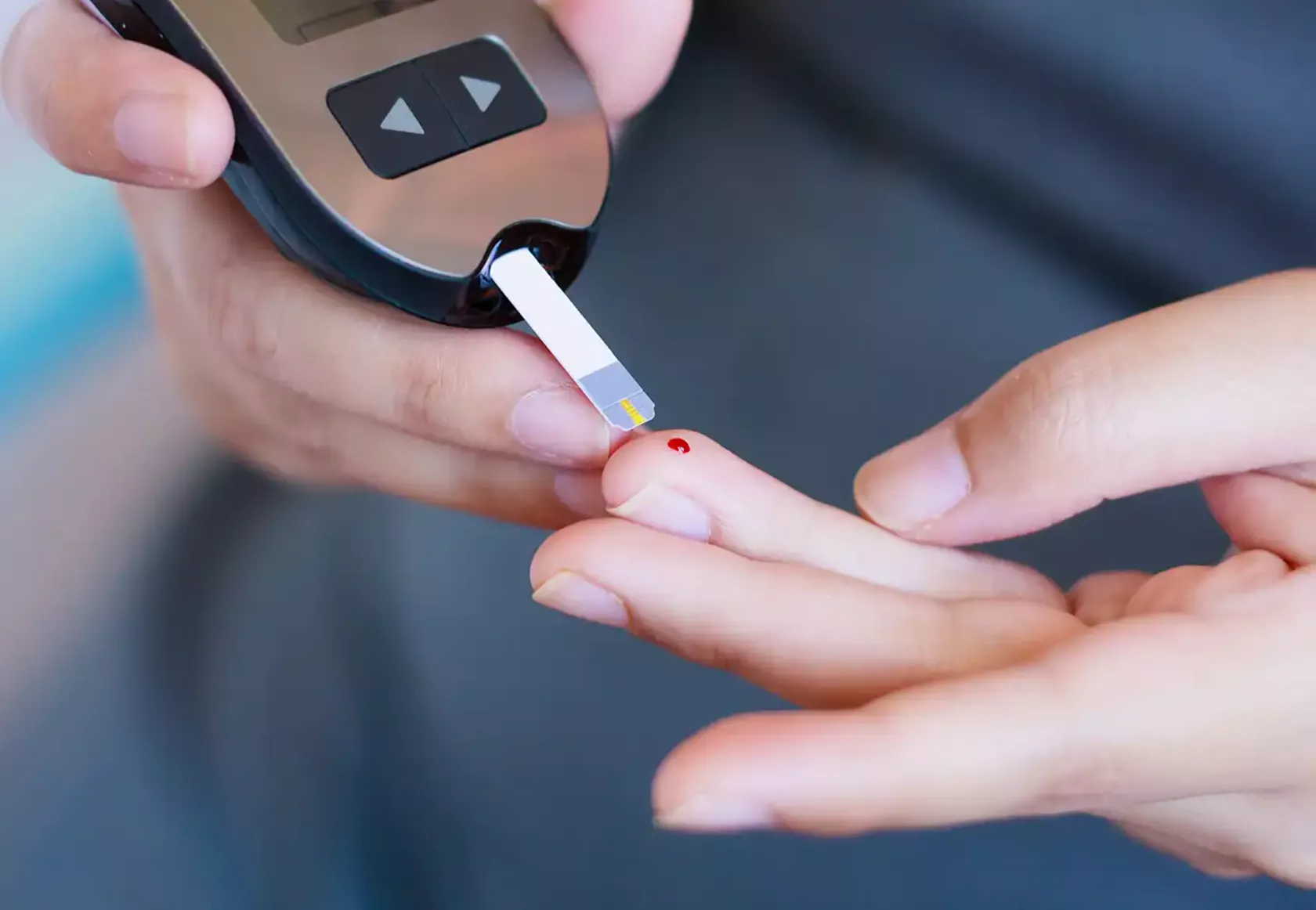 Blutglukose-Test bei Diabetes, Blutstropfen auf dem Finger und Testgerät mit Teststreifen