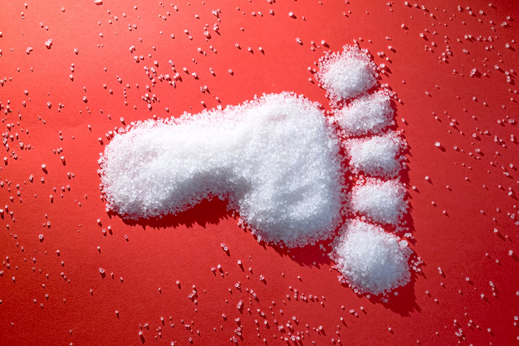 Auf rotem Grund wurde Zucker in Form eines Fußabdrucks gestreut.
