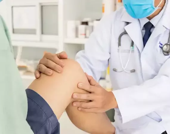 Arzt untersucht in der Praxis das Knie eines Patienten.