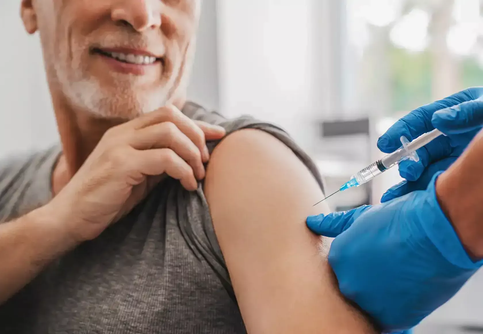 Ein älterer Mann erhält eine Impfung in den Oberarm.