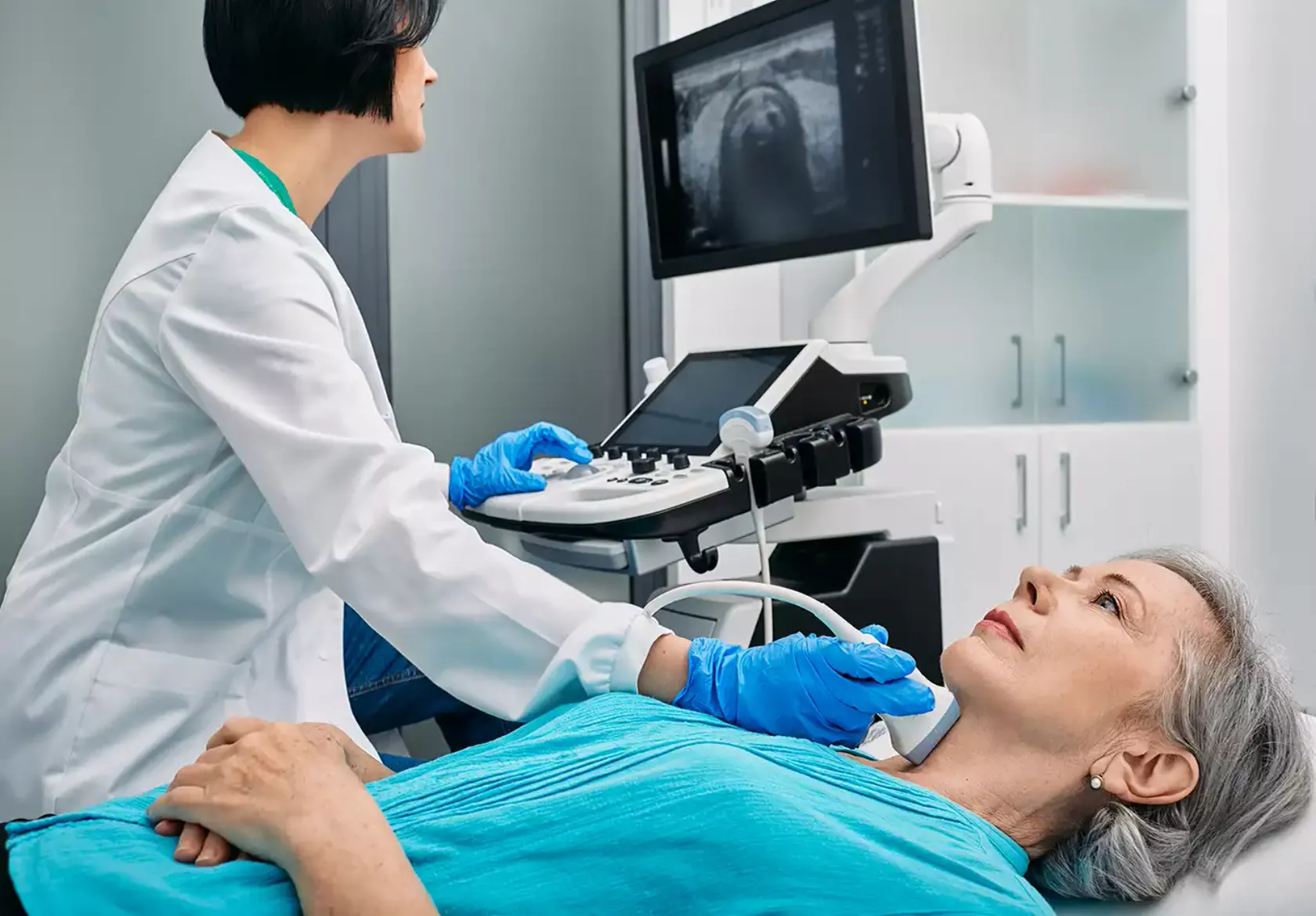 Ärztin macht ein Ultraschall von der Schilddrüse einer Patientin.