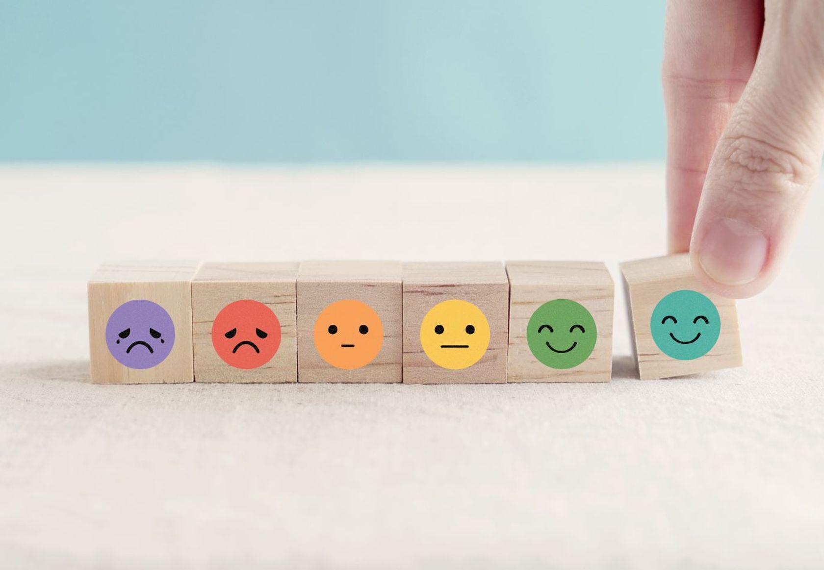 Sechs Smileys in verschiedenen Stimmungslagen, von weinend bis lachend, sind auf kleinen Holzwürfeln abgebildet. 