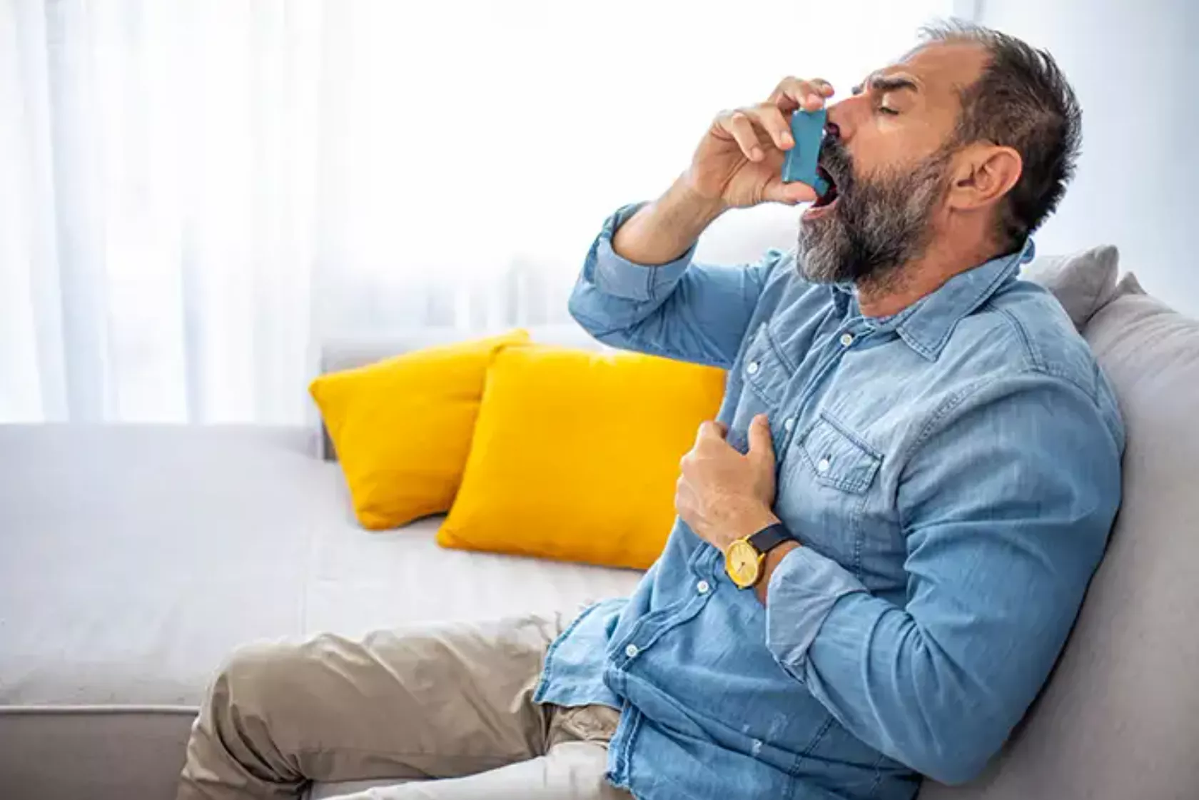Ein Mann benutzt einen Inhalator zur Erweiterung der Bronchien (Asthma-Spray).