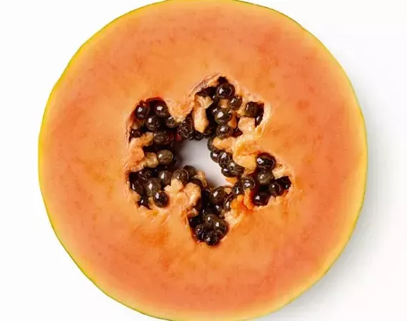 Aufgeschnitte Papaya (Querschnitt), oranges Fruchtfleisch und schwarze Kerne.